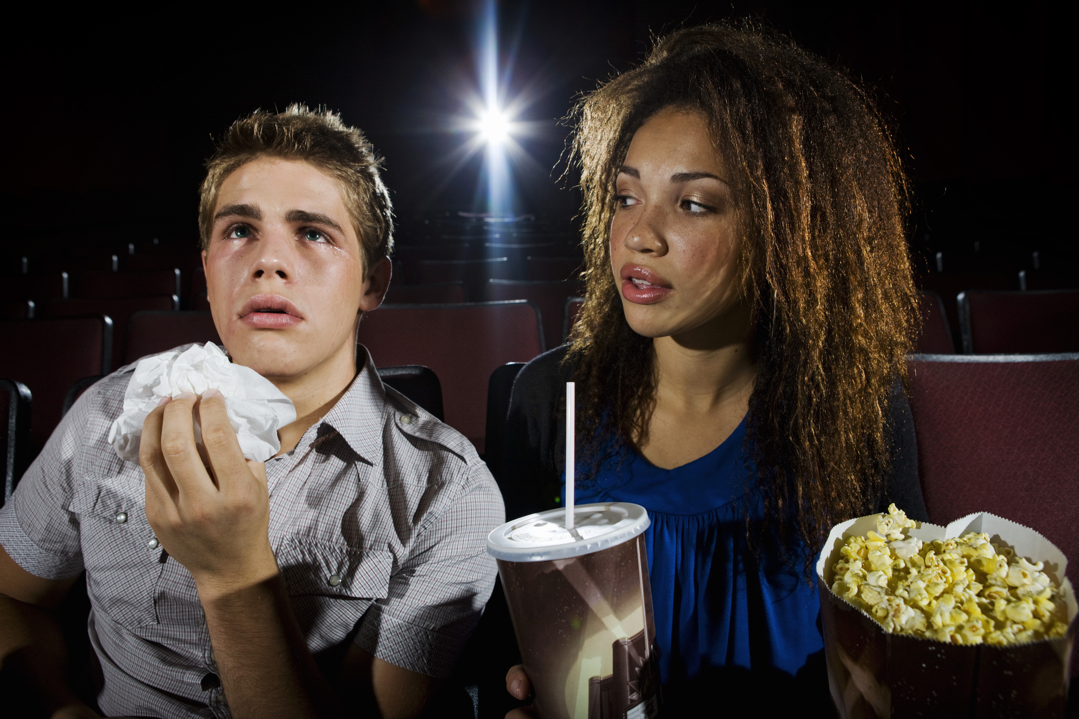 Junger Mann und junge Frau im Kino, er weint