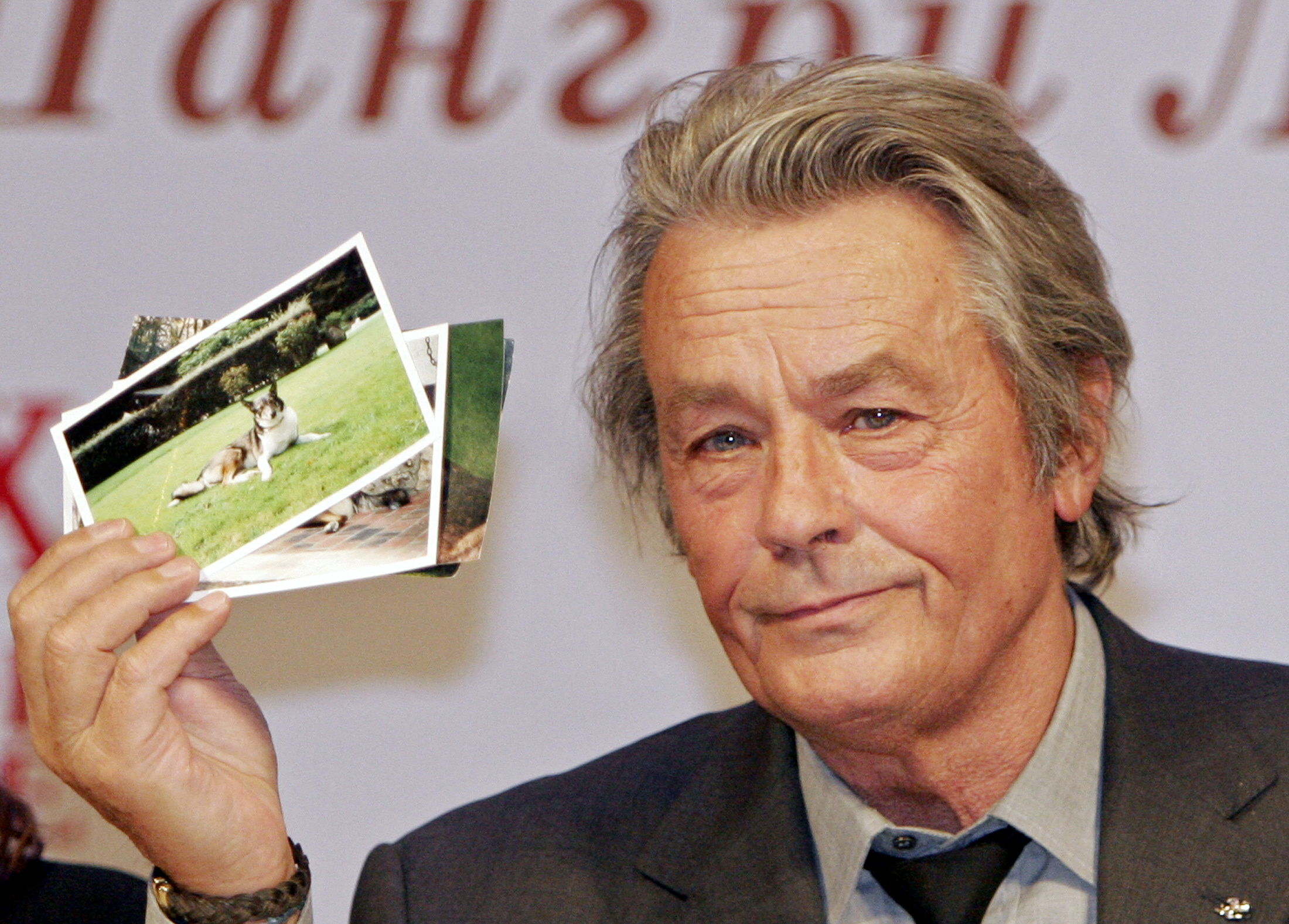 Der französische Schauspieler Alain Delon zeigt während seiner Pressekonferenz in Moskau am 16. März 2005 Bilder von zwei Hunden, die er von Alexander Lebed, einem russischen General und Politiker, der im April 2002 bei einem Hubschrauberunfall in Sibirien ums Leben kam, geschenkt bekommen hat